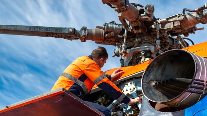 Technician - ground personnel at the airport checks the engine of the helicopter. Helicopter maintenance.