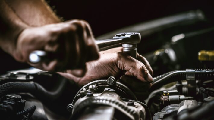 Auto mechanic working on car engine in mechanics garage. Repair service. authentic close-up shot