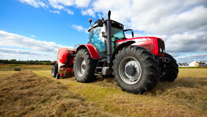 huge tractor collecting haystack in the field in a nice blue sunny day